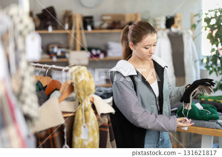 Young woman customer browsing goods and choose search gloves in store Young woman customer browsing goods and choose search gloves in store 131621817