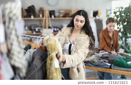 Armenian woman choosing coats and jackets in a store against the background of a customer Armenian woman choosing coats and jackets in a store against the background of a customer 131621821