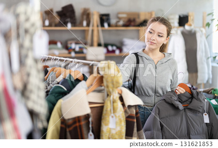 Young woman choosing a down jacket in the store for the winter 131621853