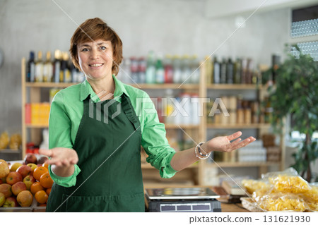 Woman seller stands in trading hall of store with goods in hand 131621930