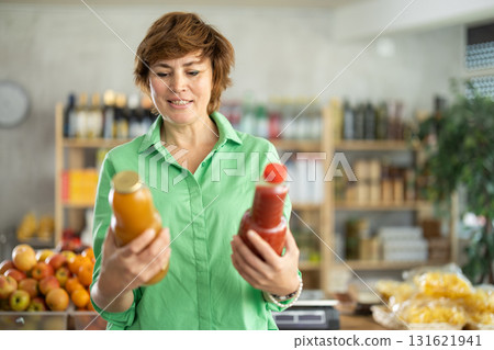 Adult woman chooses peach and tomato juices Adult woman chooses peach and tomato juices 131621941