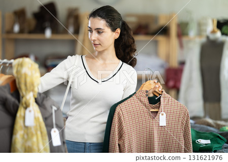 Young woman chooses warm dress in clothing store Young woman chooses warm dress in clothing store 131621976