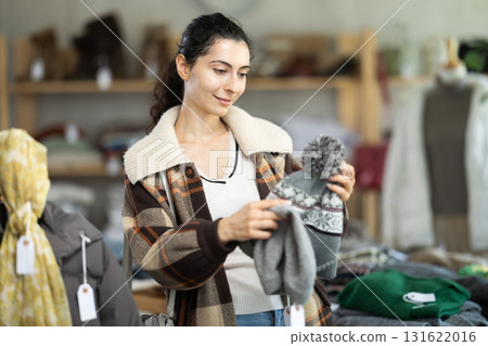 Young woman choosing hat in clothing store Young woman choosing hat in clothing store 131622016