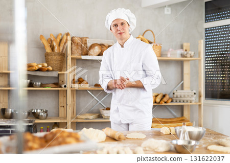 Portrait of young man baker smiling at camera posing during daily work in bakery 131622037