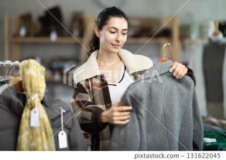 Female shopper selects clothes for autumn winter season in clothing store Female shopper selects clothes for autumn winter season in clothing store 131622045