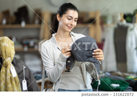 Young woman choosing fur hat in clothing store Young woman choosing fur hat in clothing store 131622072