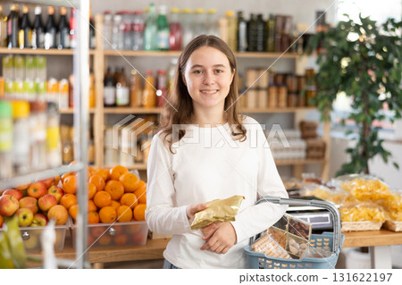 Visiting store, teen girl is looking at something on shelf of showcase. Visiting store, teen girl is looking at something on shelf of showcase. 131622197