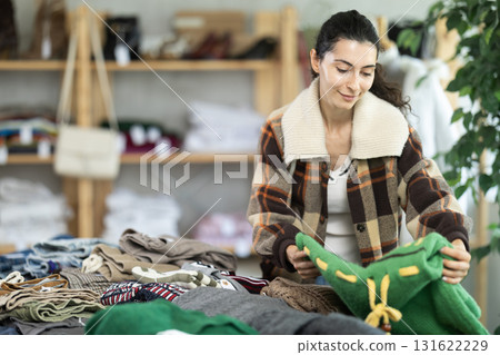 Woman carefully selects a warm sweater, pullover or cardigan in clothing store Woman carefully selects a warm sweater, pullover or cardigan in clothing store 131622229