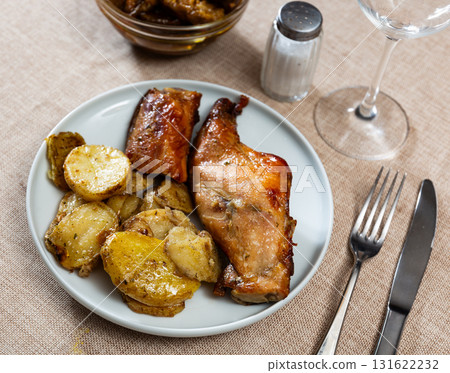 Fried rabbit cuts served with baked potatoes on plate Fried rabbit cuts served with baked potatoes on plate 131622232
