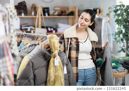 Young woman choosing coat in clothing store Young woman choosing coat in clothing store 131622245
