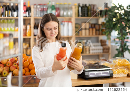 Teen girl hold packages bottles and choose consider juice in store Teen girl hold packages bottles and choose consider juice in store 131622264