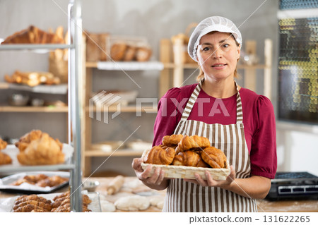 Adult female baker with basket of croissants Adult female baker with basket of croissants 131622265