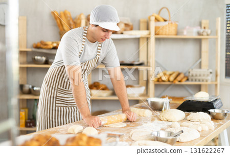 Guy worker in kitchen rolls out dough with rolling pin. Guy worker in kitchen rolls out dough with rolling pin. 131622267