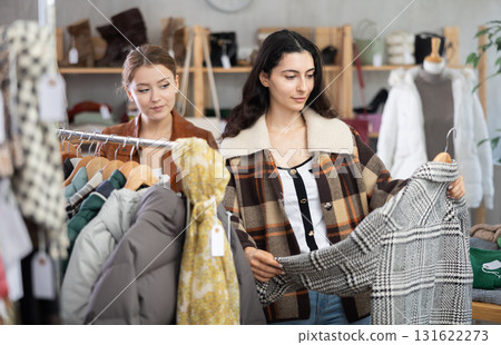 Two young women choosing outerwear in store 131622273