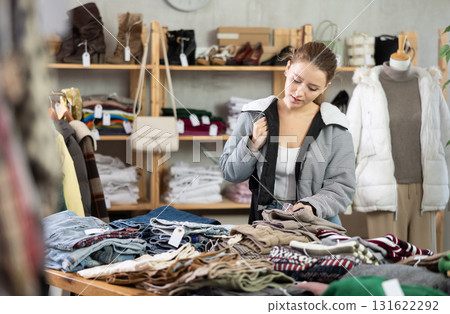 woman stands near the counter with warm pants and chooses them woman stands near the counter with warm pants and chooses them 131622292