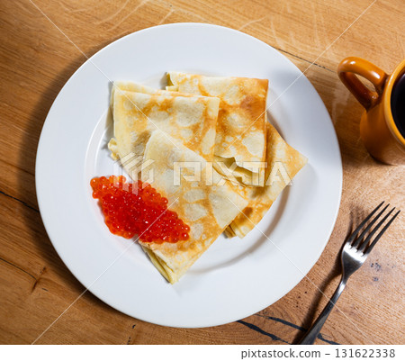 On plate - ruddy soft pancakes with spoonful fresh-grain caviar 131622338