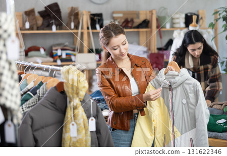Young woman choosing down jacket in clothing store Young woman choosing down jacket in clothing store 131622346