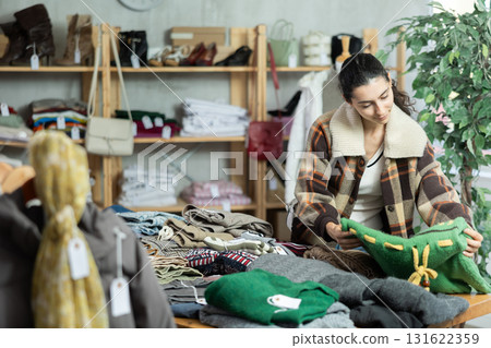 Armenian woman stands near the counter and chooses jersey sweaters Armenian woman stands near the counter and chooses jersey sweaters 131622359