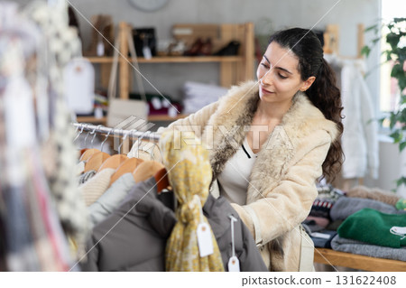 Young woman chooses outerwear in store 131622408