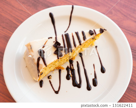 Slice of biscuit cake with white chocolate icing and dark chocolate topping 131622411