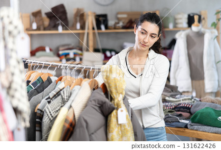 Young woman chooses outerwear in store Young woman chooses outerwear in store 131622426