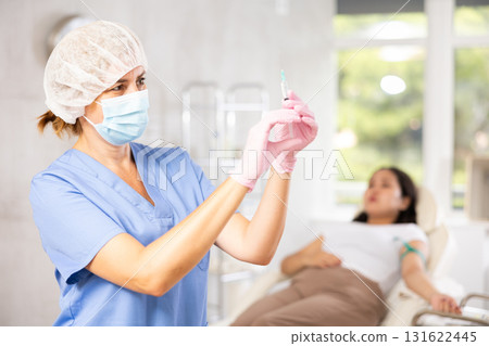 Middle-aged doctor giving injection into vein Middle-aged doctor giving injection into vein 131622445