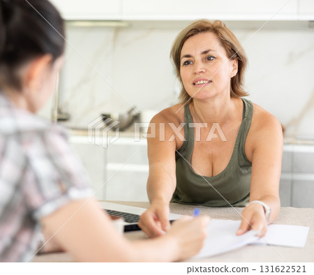 Woman listen attentively to woman of seller, who tells about advantages of making microloan in credit institution Woman listen attentively to woman of seller, who tells about advantages of making microloan in credit institution 131622521