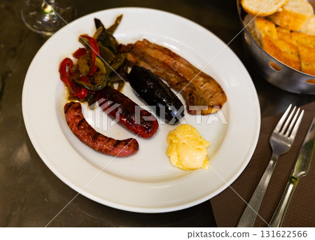 Grilled sausages and meat served with stewed vegetables and wine Grilled sausages and meat served with stewed vegetables and wine 131622566