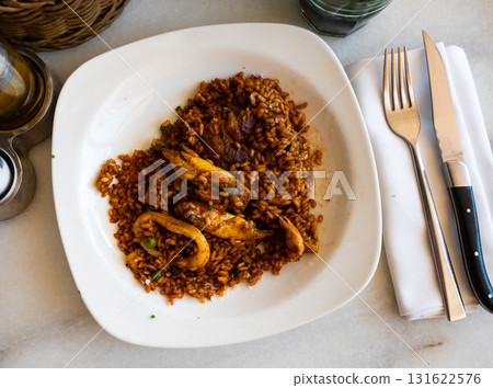 Plate is filled with paella made according to Spanish recipe from rice cereals, seafood, and chicken 131622576