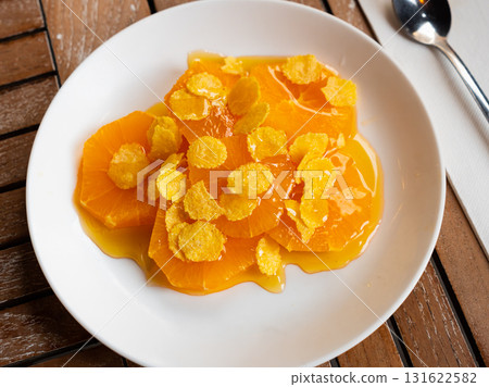 Healthy breakfast, lunch or snack on plate. Orange slices with honey and sprinkled with corn flakes 131622582