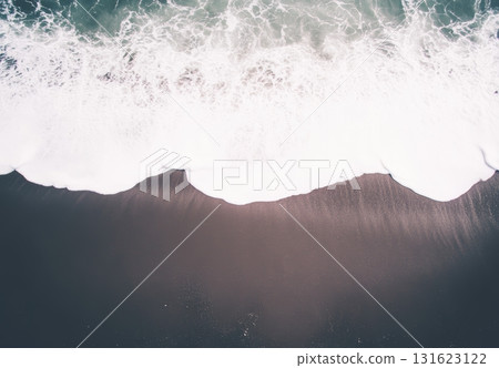 Waves crashing on a sandy beach with soft sunlight at midday 131623122