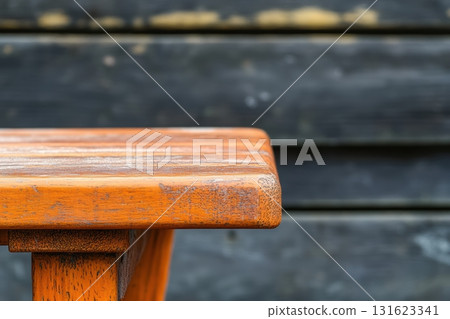 Wooden table edge against a rustic black backdrop outdoors during the day 131623341