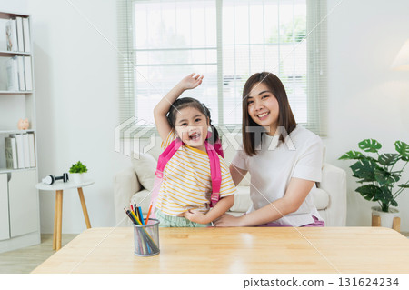 Happy child with backpack poses with smiling mother at home during study time showing parental bonding and learning environment in bright room Happy child with backpack poses with smiling mother at home during study time showing parental bonding and learning environment in bright room 131624234