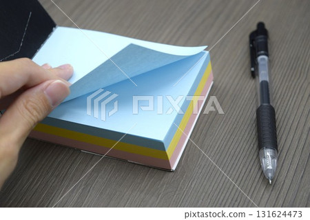 Ballpoint pen and hand turning over notepad 131624473