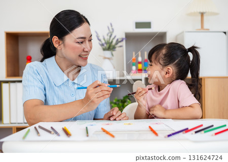 toddler baby girl training to drawing with colored pencil with mother helping on desk at home toddler baby girl training to drawing with colored pencil with mother helping on desk at home 131624724