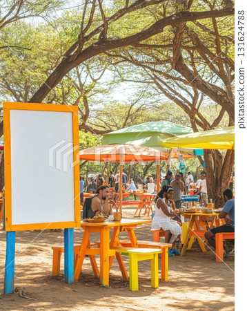 People Dining At A Colorful Outdoor Cafe Under Lush Green Trees And Bright Umbrellas In Sunshine 131624788