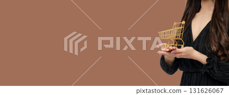 Woman with a mini shopping cart on brown backdrop 131626067