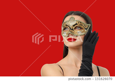 Woman with dark hair and red lips adorned in a gold mask 131626070