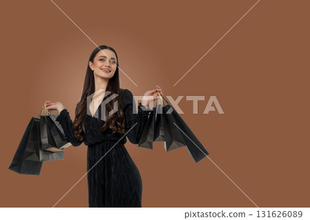 Woman smiles while holding shopping bags in a stylish outfit 131626089