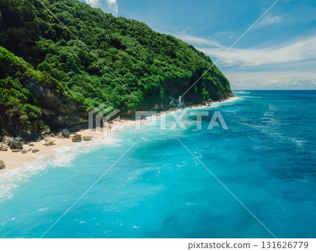 Aerial view of coastline with turquoise ocean and tropical beach under rocky cliffs. Aerial view of coastline with turquoise ocean and tropical beach under rocky cliffs. 131626779