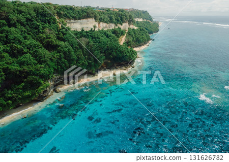 Aerial view of coastline with turquoise ocean and tropical beach under rocky cliffs. Aerial view of coastline with turquoise ocean and tropical beach under rocky cliffs. 131626782