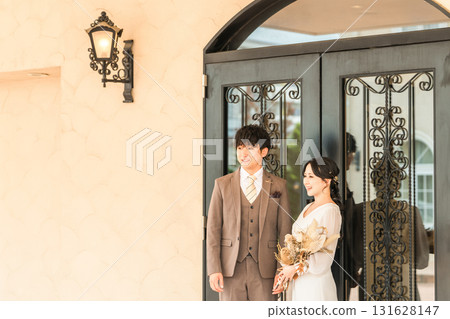 Bride and groom in front of the door to the wedding reception hall 131628147