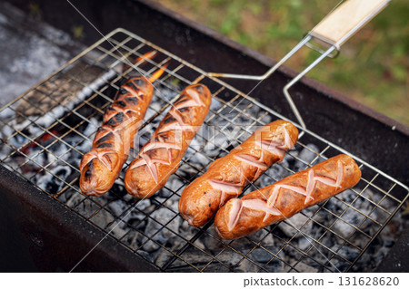 Fried and juicy grilled sausages on a bareky grill in close-up. picnic items and delicious food. Fried and juicy grilled sausages on a bareky grill in close-up. picnic items and delicious food. 131628620
