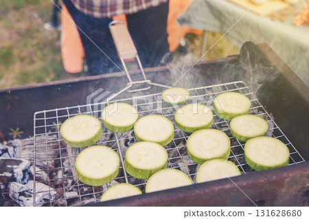 Grilled sliced eggplant on a charcoal grill during an autumn picnic gathering in a cozy outdoor setting 131628680