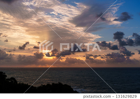 南紀勝浦市熊野灘的黎明。朝陽的光芒透過雲層灑向天空,天空從金色變成了鈷藍色。 南紀勝浦市熊野灘的黎明。朝陽的光芒透過雲層灑向天空,天空從金色變成了鈷藍色。 131629829