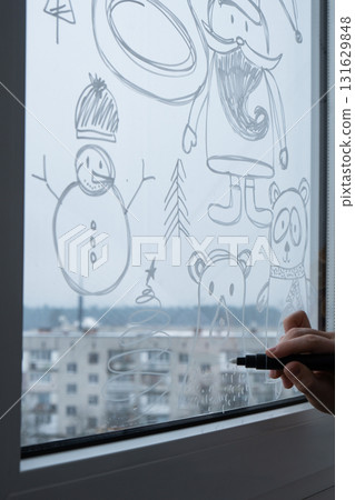 Sustainable responsible holiday decor. Female hand painting bear painted on window glass indoor at home. Christmas winter decoration. White pattern. Snow art tracery on season. Diy Sustainable responsible holiday decor. Female hand painting bear painted on window glass indoor at home. Christmas winter decoration. White pattern. Snow art tracery on season. Diy 131629848