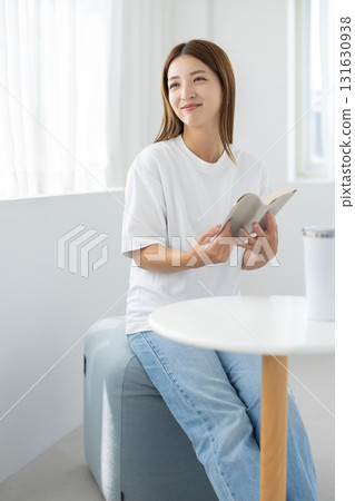 年輕女子在明亮的房間裡微笑著看書 131630938