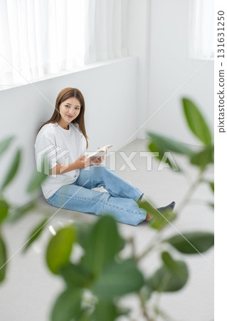A young woman sitting on the floor in a bright room and enjoying reading A young woman sitting on the floor in a bright room and enjoying reading 131631250