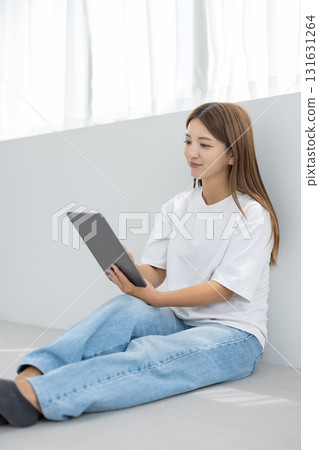 Smiling young woman holding a tablet in a bright room 131631264