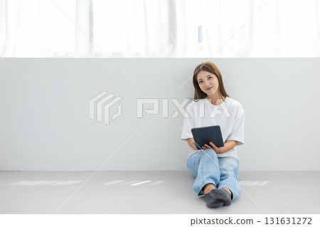 Smiling young woman holding a tablet in a bright room 131631272